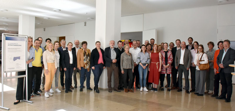 Die Teilnehmenden der 20. Sitzung der ARE-Vet auf einem Gruppenfoto. Links im Bild ein Poster der ARE-Wanderausstellung.